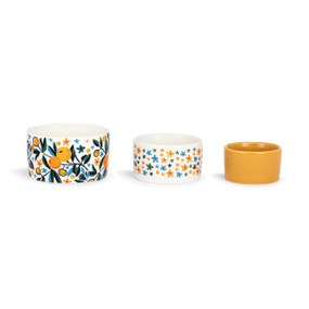 A set of three small ceramic nesting bowls in orange, blue and white citrus and floral patterns.
