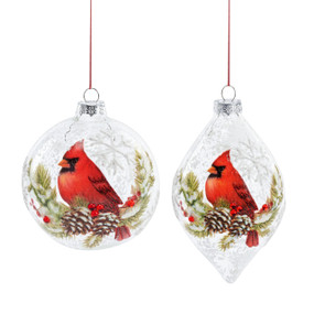 Two different clear glass ornaments with an illustrated red cardinal bird perched on a evergreen branch.
