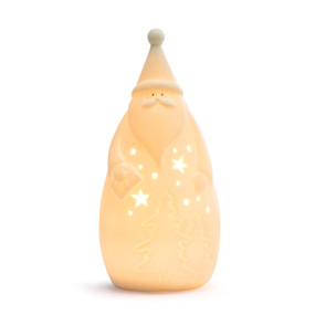A white ceramic Santa holding a gift that lights up, displayed lit up.