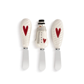 A set of three small metal spreaders with white ceramic handles. Two of the handles have a red heart and the other is shaped like a snowman.