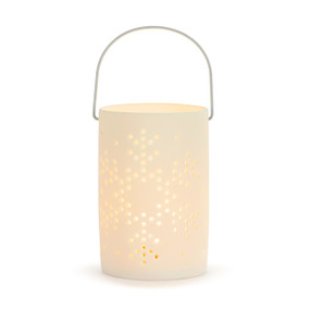 A white round ceramic lantern with a wire handle and a cut out image of a snowflake displayed lit.