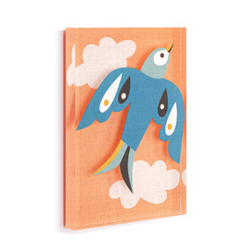 A light orange acrylic wall art tile with an illustrated modern blue bird in flight among the clouds displayed angled to the right.