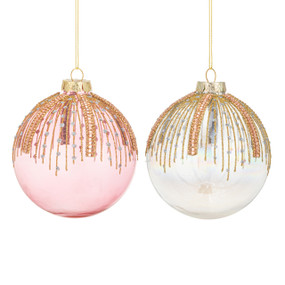 Two round ornaments in pink and white with gold ornamentation coming down in trails from the top.