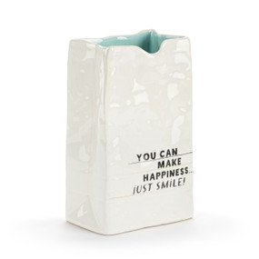 A small white ceramic vase that looks like a crinkly paper bag. The interior is light blue and the saying "You can make happiness...just smile" on the front.