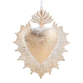 A gold heart shaped ornament with rays coming out from the heart and ornamentation on top.