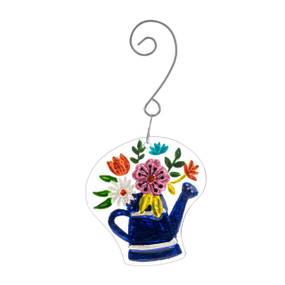 A glass ornament of a blue watering can filled with colorful flowers hanging from a curved silver hanger.