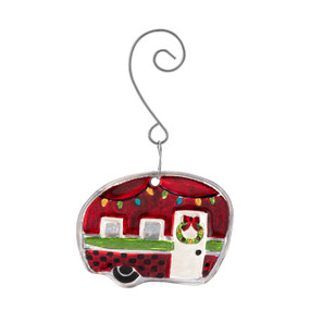 A red glass ornament of a camper van decorated for the holidays with a curved silver hanger.