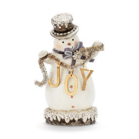 A white snowman figure where he is holding a length of tinsel with JOY hanging from it. The snowman is decorated with silver glitter and beads.