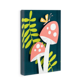 A dark green acrylic wall art tile with two illustrated mushrooms in front of a leafy branch displayed angled to the right.