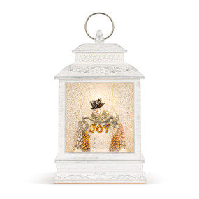 A white lit musical lantern with the image of a snowman holding a green swag with the word "Joy".