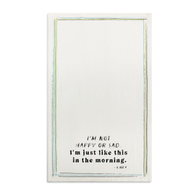 A white kitchen towel with the saying "I'm not happy or sad I'm just like this in the morning" displayed laid out flat.