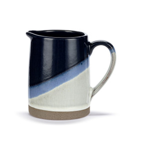 A mini blue and white ceramic pitcher with a an ombre color change from white to dark blue and a tan textured base.