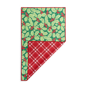 A rectangular double sided towel. One side is green with illustrated holly leaves and the other is red and white plaid, displayed with the red corner turned back.