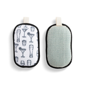 A set of two absorbent sponges in black and white with illustrated cocktails. Each has a fabric tab at the top for hanging.