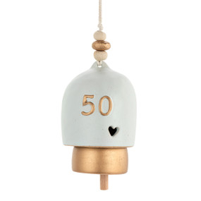 A cream and gold ceramic bell with the number 50 in gold on the front and a cut out heart.