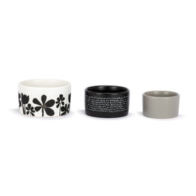 A set of three small ceramic nesting bowls in white, grey and black floral and dot patterns.