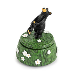 A figurine of a black bear swinging a little bear cub around on top of a grassy field of white flowers which is a musical base.