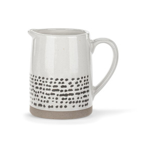 A mini cream pitcher with a handle and textured tan base. There are small gray marks along the bottom half.