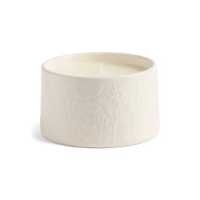 A three wick gardenia citronella candle in a cream ceramic container with botanical images around it.