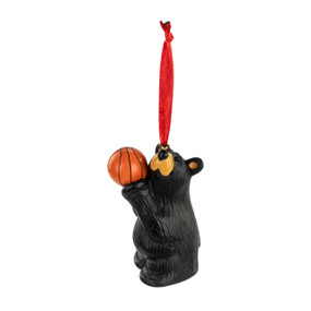 An ornament of a black bear playing with a basketball. The ornament has a red ribbon hanger.