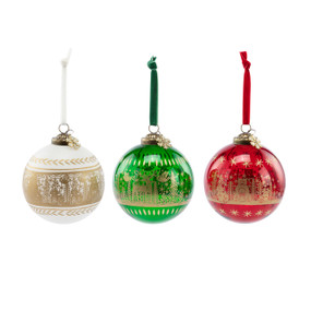 A set of three round glass ornaments each with a winter woodland scene in gold foil on a white, green or red background.