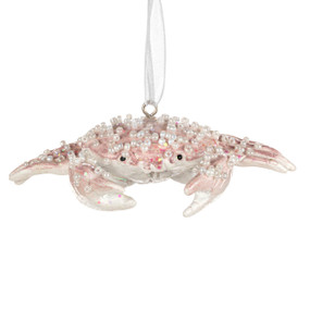 A light pink crab shaped ornament decorated with white beads.