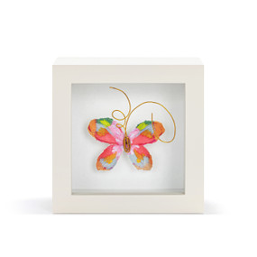A pink and orange butterfly with gold wire tentacles in a white shadow box.