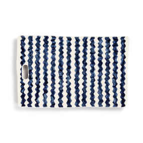 A white ceramic cutting board with dark blue zig zag stripes.