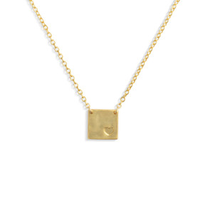 A gold chain necklace with a square gold charm with a heart in the corner.