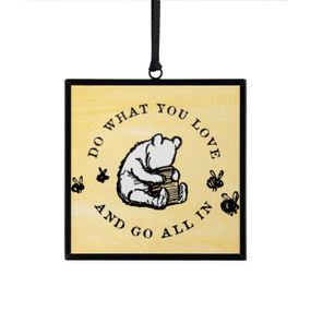 A small square yellow sun catcher with a classic illustration of Pooh eating honey and the saying "Do What You Love and Go All In".