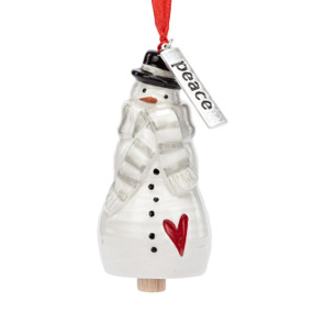 A small white bell shaped like a snowman wearing a gray and white striped scarf and has a silver metal tag with the word "peace" at the top.