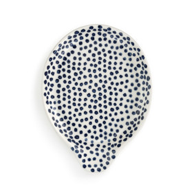 A white ceramic spoon rest with dark blue dots.