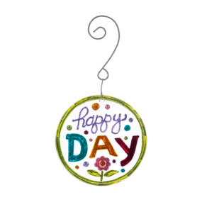 A glass ornament with the saying "happy day" and a small flower  hanging from a curved silver hanger.