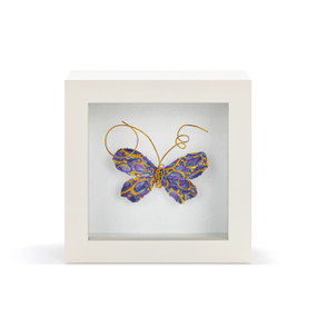 A purple and gold butterfly with gold wire tentacles in a white shadow box.