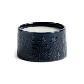 A three wick cedarwood citronella candle in a navy blue ceramic container with botanical images around it.