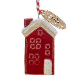 A small ceramic red house shaped ornament with snow on the roof and a gold metal tag at the top with the word "love".