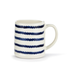 A white ceramic mug with dark blue zig zag stripes.