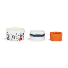 A set of three small ceramic nesting bowls in white, blue and orange wildflower and stripe patterns.
