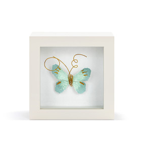 A light green butterfly with gold wire tentacles in a white shadow box.