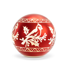 A red glass globe ornament with a cardinal image. The globe is displayed lit.