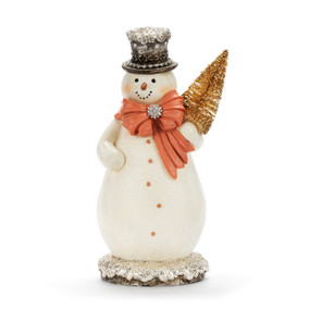 A white snowman figure wearing an orange bow and holding a small gold tree. The snowman is decorated with silver glitter and beads.