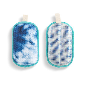 A set of two absorbent sponges in a blue and white tie dye pattern. Each has a fabric tab at the top for hanging.