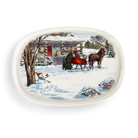 An oval white ceramic platter with an illustrated winter scene of a horse drawn sleigh and snowman out in front of a home decorated for the holidays.