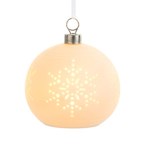 A white ceramic ornament that lights up with snowflake cut outs displayed lit.