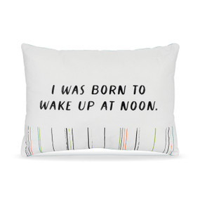 A small white accent pillow with the saying "I was born to wake up at noon".
