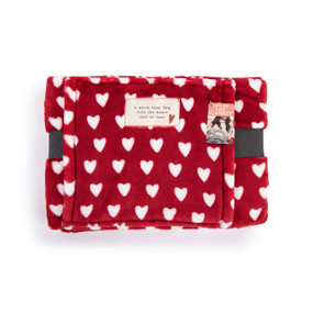 A red blanket covered in white hearts with a fabric patch that says "a warm coxy hug fills the heart full of love".