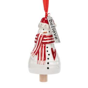 A small white bell shaped like a snowman wearing a red and white striped scarf and has a silver metal tag with the word "believe" at the top.