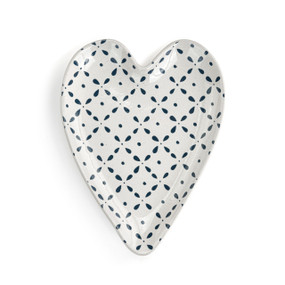 A white heart shaped spoon rest with small dark blue dots and petal shapes.