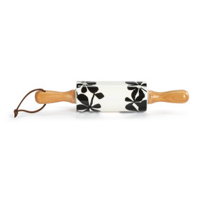 A small white decorative ceramic rolling pin with wood handles and a bold black flower illustration on the roller.