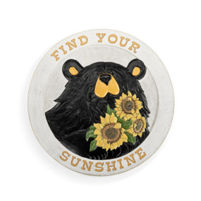 A white round garden stone with the saying "Find Your Sunshine" around the rim and the image of a black bear holding sunflowers in the middle.